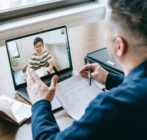 A man is sitting at the desk and hosting a video-meeting