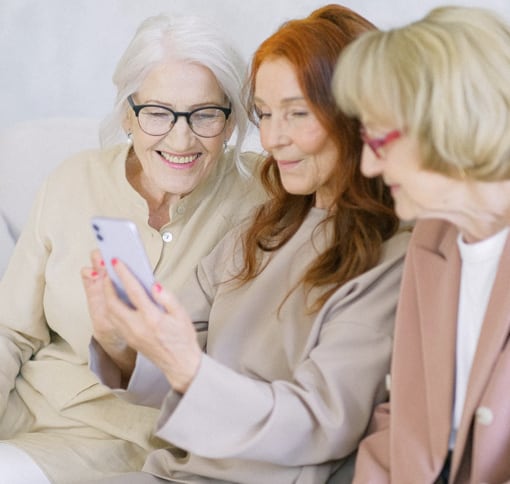 A group of three older women chats over the mobile video-chat